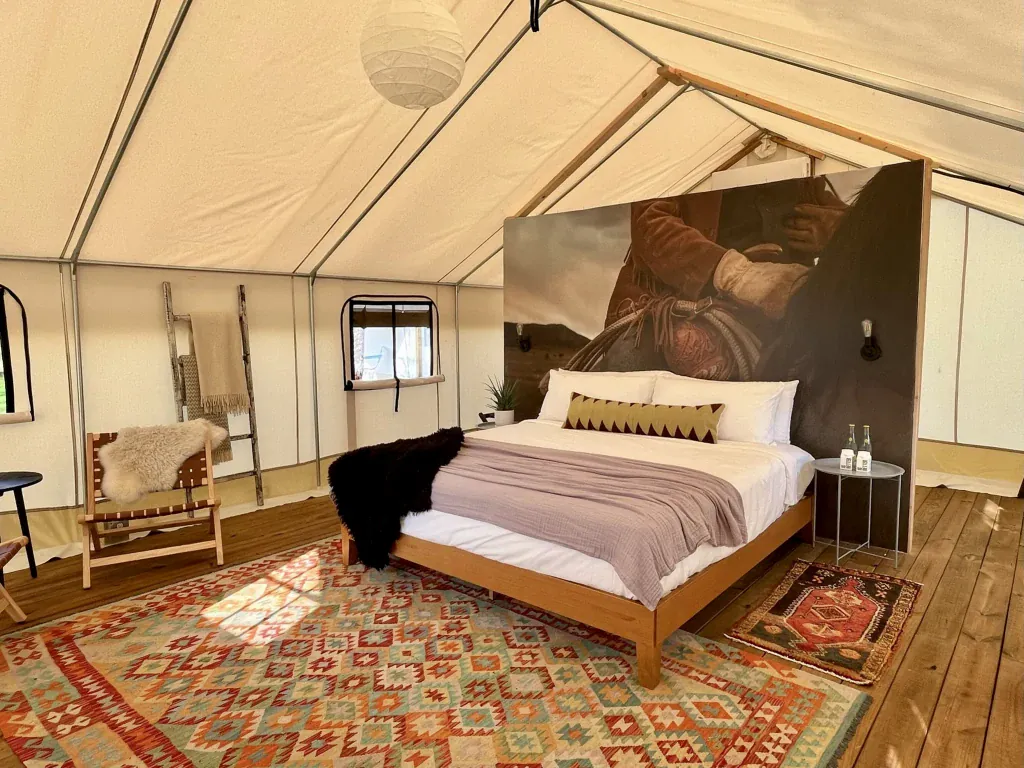 Safari tent interior with a bed, seating, and Western decor