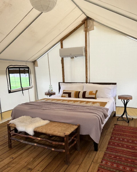 Bright safari tent interior with bed and patterned rug at Rancho Moonrise