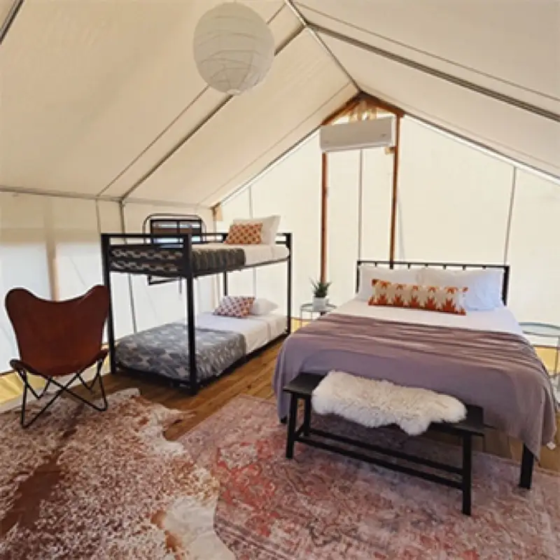 Family safari tent interior with queen bed and bunk beds at Rancho Moonrise