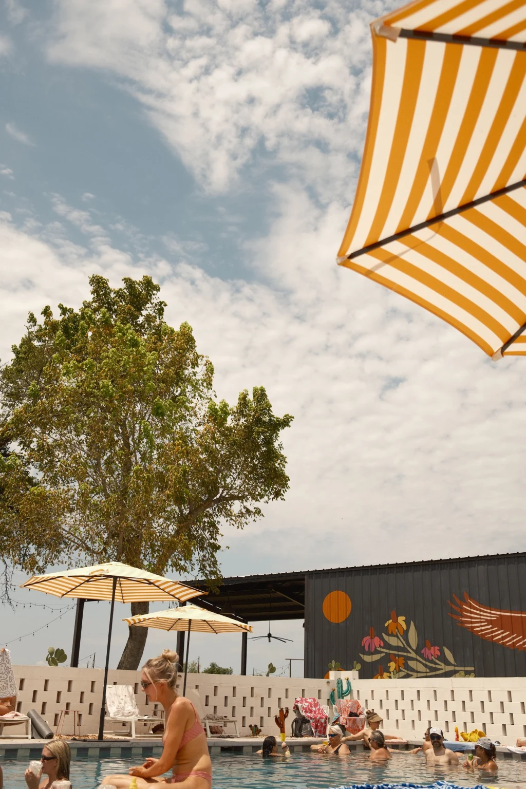 Guests enjoying the pool under a striped umbrella at Rancho Moonrise
