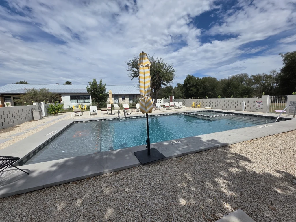 Pool with yellow and white striped umbrella on a clear-sky day